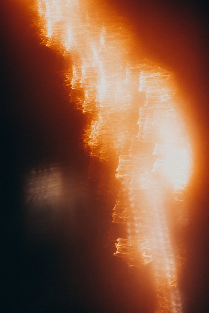 Dynamic abstract image of bright orange light streaks over dark background.